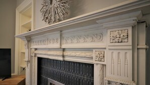 A fireplace with intricate white carvings and a decorative piece above it. - Linden House - Flat 3 - Airdrie (Airdrie)