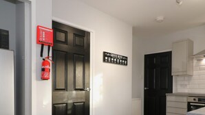 A modern kitchen with a black door, white walls, and a wooden floor. - Sunnyside House - Holytown (Motherwell)