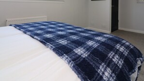 A bedroom with a bed, a window, a door, and a wall-mounted light fixture. - Sunnyside House - Holytown (Motherwell)