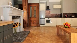 Una cocina moderna con piso de madera, horno empotrado y refrigerador.