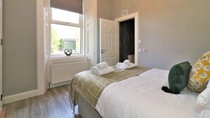 Un dormitorio con cama, ventana, radiador y puerta.