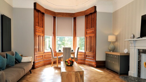 Amplia sala de estar con piso de madera, un sofá, una mesa de centro y una chimenea.