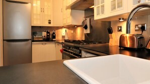 A modern kitchen with stainless steel appliances, white cabinetry, and a black countertop. - Shield House - Govan (Glasgow)