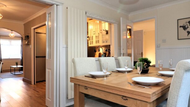 A dining area with a wooden table set for four, a bench, and a hanging light fixture. - Shield House - Govan (Glasgow)
