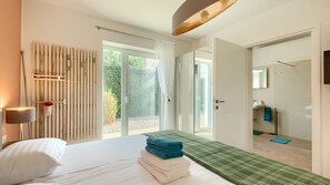Un dormitorio moderno con una cama grande, una pared de listones de madera y vistas al jardín a través del ventanal.