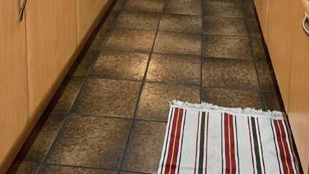 A kitchen with wooden cabinets, a microwave, and a tiled floor.