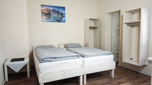 A bedroom with a bed, a bedside table, a wardrobe, and a painting on the wall.