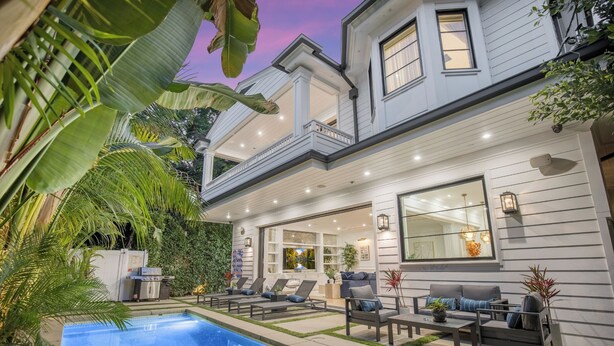 A two-story house with a pool, outdoor seating, and a large window overlooking the pool.