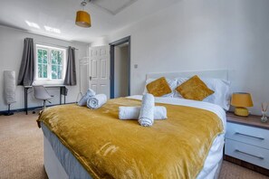 A hotel room with a bed, a desk, a chair, a window, and a door.
