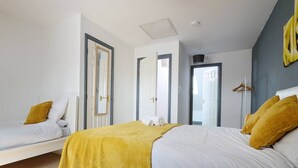 Ein modernes Schlafzimmer mit einem großen Bett, einem kleineren Bett und einem begehbaren Kleiderschrank.
