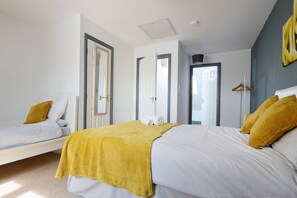 Un dormitorio moderno con una cama grande, una cama más pequeña y un vestidor.