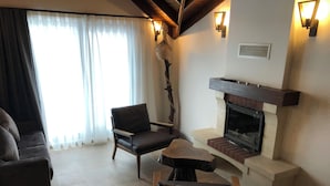 A living room with a fireplace, a sofa, and a chair. - MASKLAVİ (Kestel)