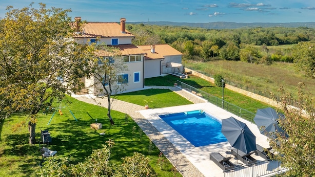 Une maison avec une piscine, un jardin et une vue sur la campagne.
