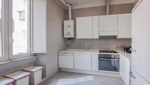 Een compacte keuken met witte kastjes, een ingebouwde vaatwasser en een gasfornuis.
