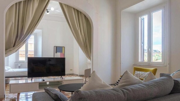 Een moderne woonkamer met een bank, een televisie en een eethoek.