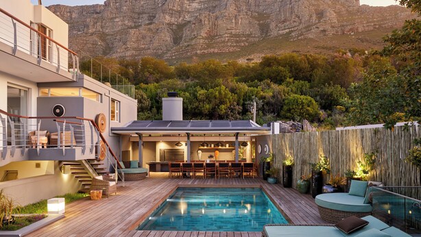 Una casa moderna con piscina, angolo bar esterno e vista su una montagna.