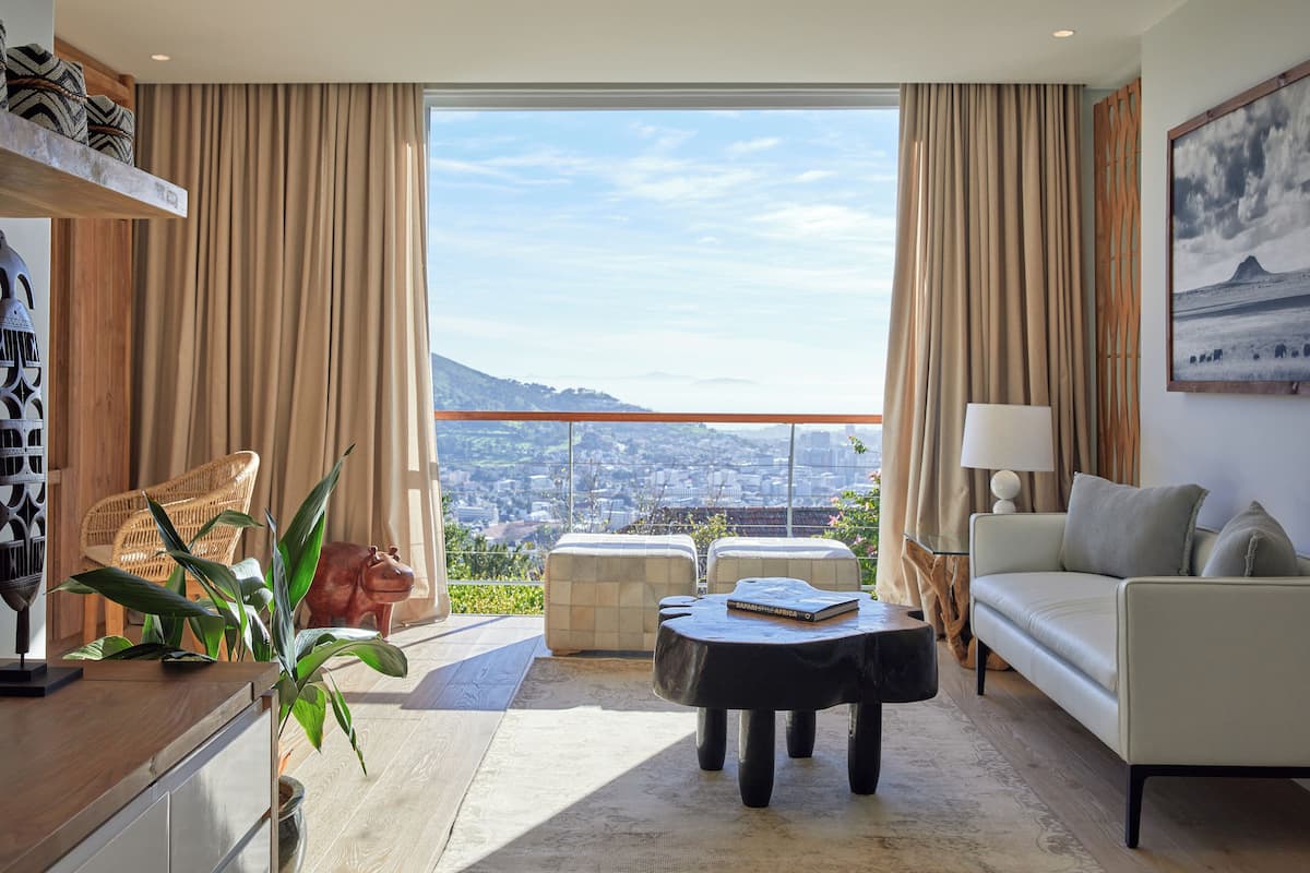 Ein geräumiger Wohnbereich mit Sofa, Couchtisch und Sesseln, mit einem großen Fenster und Blick auf die Stadt.