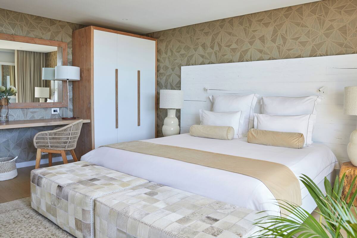Ein Hotelzimmer mit einem großen Bett, einem Kleiderschrank, einem Schreibtisch mit Stuhl und einem Spiegel.