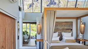 Una camera da letto moderna con una testiera in legno, un letto grande e vista sull'esterno attraverso ampie finestre.