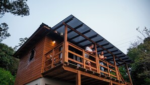 A wooden cabin with a balcony and a covered upper level. - Tilli's Haus Praia & Campo (Florianópolis)