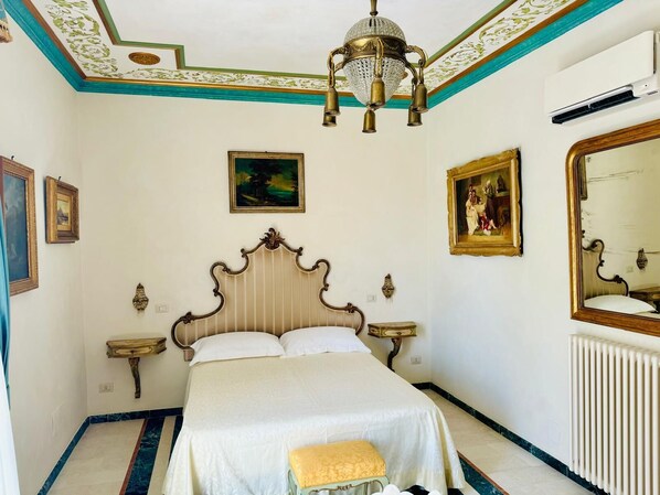 Une chambre à coucher avec un grand lit, un plafond décoré et des œuvres d’art aux murs.