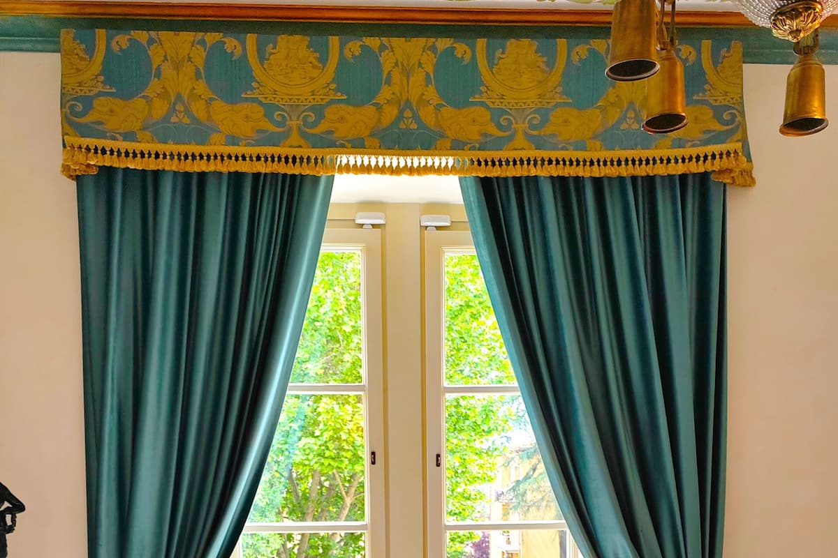 Une pièce dotée de deux portes, de rideaux de couleur turquoise et d’un plafond orné de motifs.