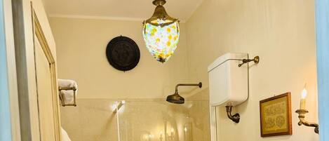A bathroom with a glass-enclosed shower, a toilet, a sink, and a wall-mounted light fixture.