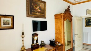 Een kamer met een houten kast, een televisie, een ingelijst schilderij en een deur naar een andere kamer.