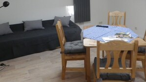 A compact living space with a sofa, a dining table with chairs, and a ceiling light fixture.