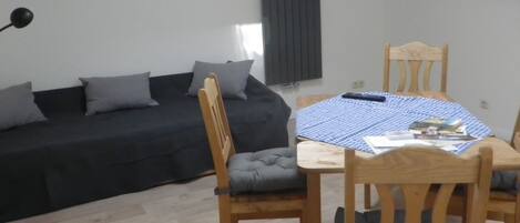 Un espace de vie compact comprenant un canapé, une table à manger avec des chaises et un luminaire suspendu au plafond.