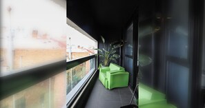 A narrow balcony with a green planter and a window overlooking a cityscape. - Stylish 1BDR in the heart of Trendy Fitzroy (Melbourne)