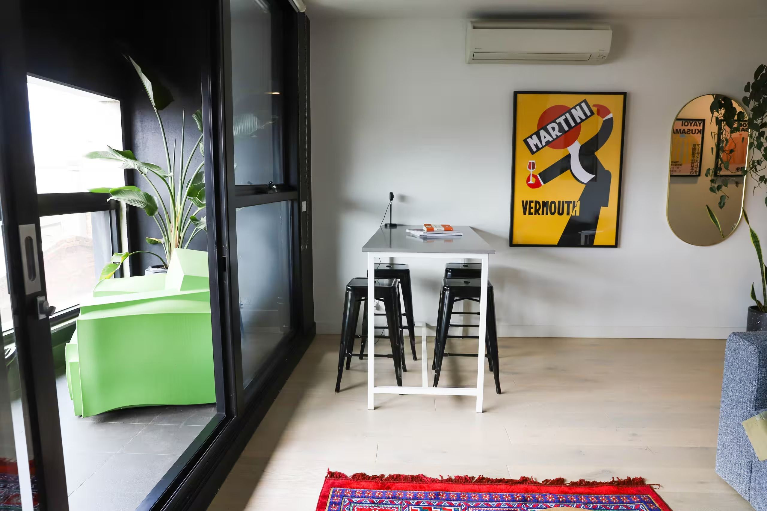 A modern interior with a dining area, a green plant, and a poster on the wall.