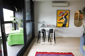Un intérieur moderne avec un coin repas, une plante verte et une affiche accrochée au mur.