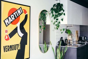 Une cuisine avec une grande affiche encadrée, un miroir et des plantes en pot.