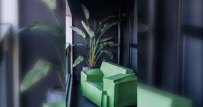 A modern interior with a potted plant and geometric green furniture against a dark wall. - Stylish 1BDR in the heart of Trendy Fitzroy (Melbourne)