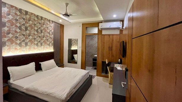 Une chambre moderne avec un grand lit, une armoire en bois et un ventilateur de plafond.