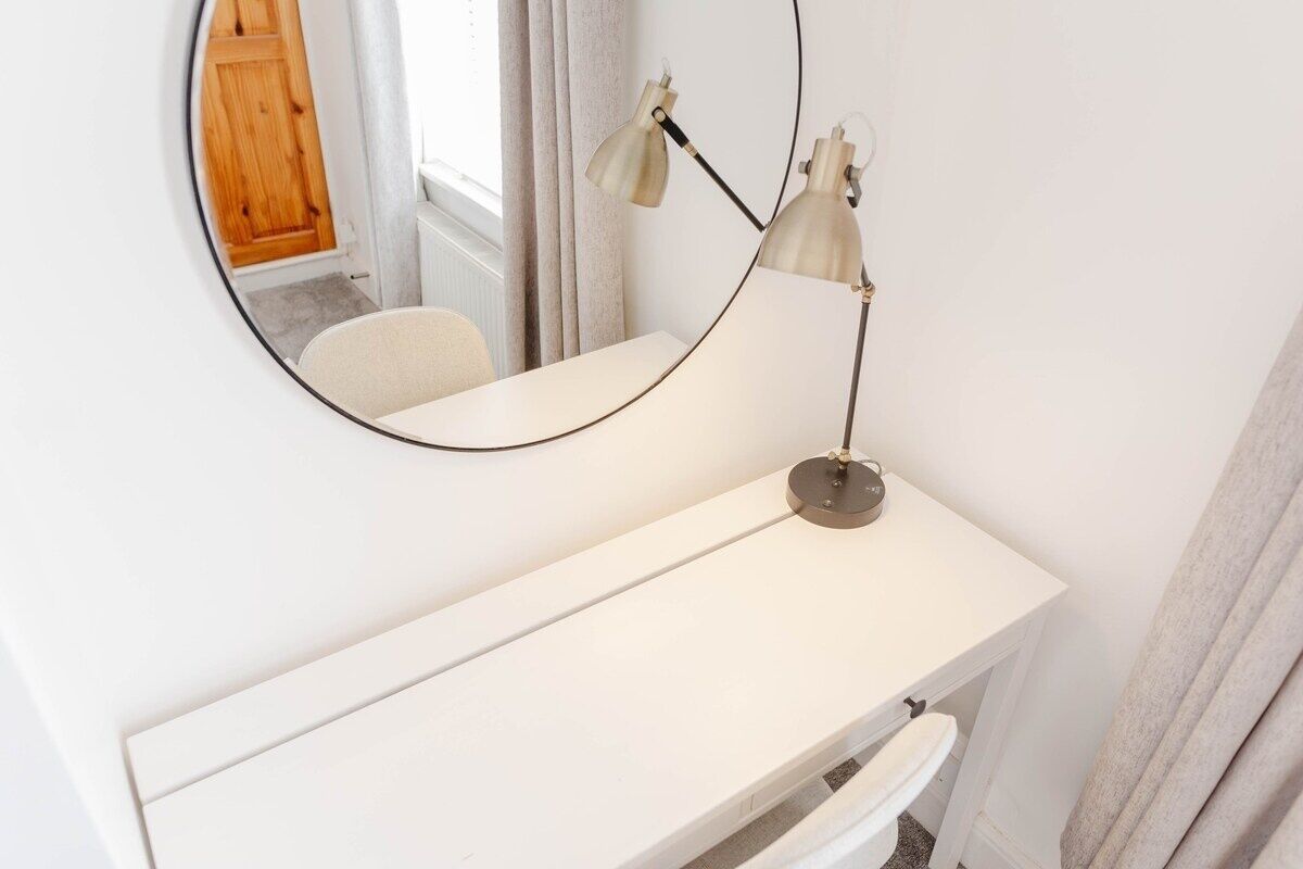 A white vanity with a round mirror and two lamps.