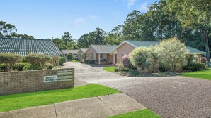 A residential area with a private property sign, houses with green roofs, and a gravel driveway.