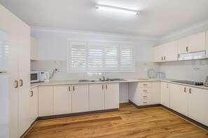Kitchen features white cabinetry, stainless steel sink, and microwave.