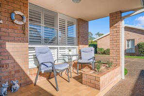Relax in this charming outdoor seating area with a table and two comfortable chairs.