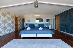 Una camera da letto moderna con un letto grande, un comodino, uno specchio e un bagno visibile attraverso una porta aperta.