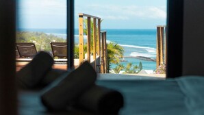 A bed with pillows, a view of the ocean, and a wooden deck with chairs. - Luxueuse Villa Calypso - Piscine et vue mer à Saint Gilles les Bains (Saint Gilles les Bains)