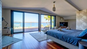 A bedroom with a large bed, a TV, and a view of the ocean. - Luxueuse Villa Calypso - Piscine et vue mer à Saint Gilles les Bains (Saint Gilles les Bains)