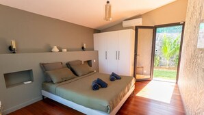 A bedroom with a bed, a wardrobe, a small shelf, and a sliding glass door leading to an outdoor area.