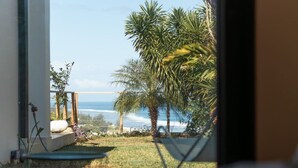 A view from inside a room to a balcony with a palm tree and ocean. - Luxueuse Villa Calypso - Piscine et vue mer à Saint Gilles les Bains (Saint Gilles les Bains)