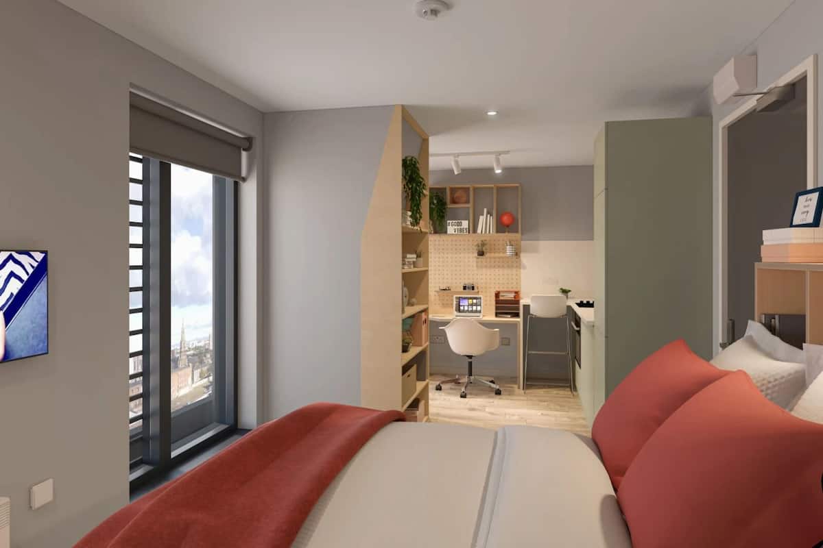 A modern bedroom with a large bed, a desk, and a view of a cityscape through a window.
