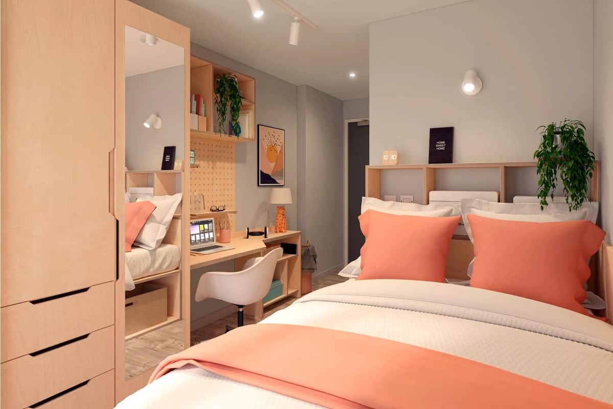 A bedroom with a bed, desk, chair, wardrobe, and shelves with books and plants.