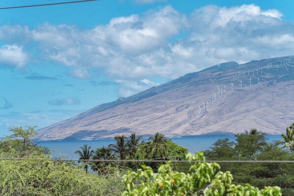 Paisaje montañoso con aerogeneradores y una masa de agua.