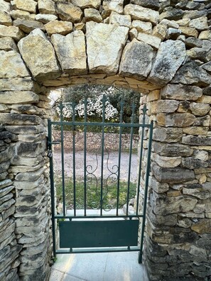 Enter a serene garden oasis through this rustic stone archway, leading to a beautifully maintained outdoor space.