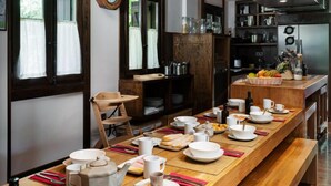 Una cocina moderna con encimeras de madera, una larga mesa de comedor dispuesta para una comida, y un reloj en la pared.